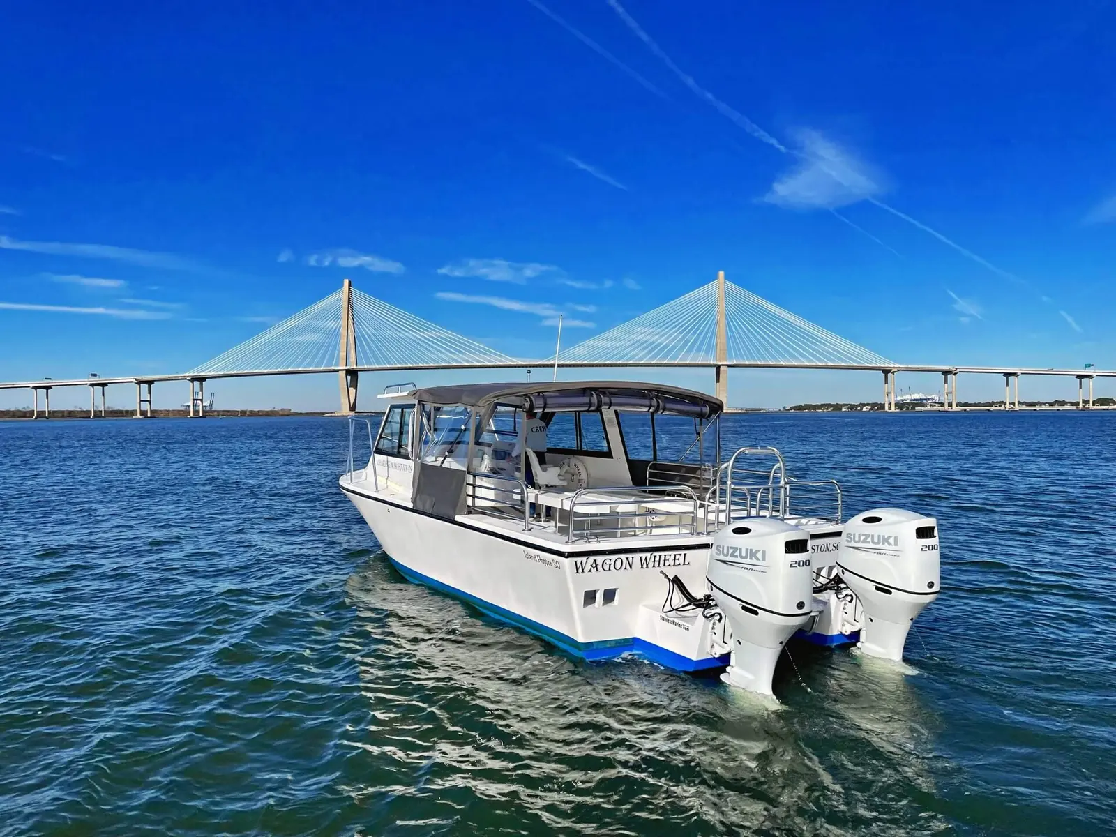 Wagon Wheel charter boat crossing Charleston harbor beneath the Ravenel Bridge on a bright day